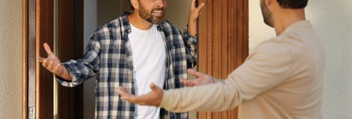 תמונה נושא של המאמר עורך דין סכסוך שכנים המציגה שני גברים מתווכחים מחוץ לבית כשאחד מהם מביע כעס באמצעות שפת הגוף שלו.